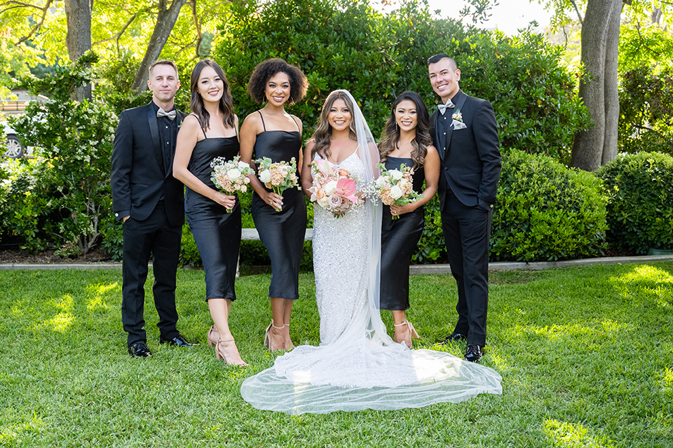  a modern black and white wedding with crystal details -the bride in a lace formfitting gown and the groom in a white + black tuxedo – bridesmaids