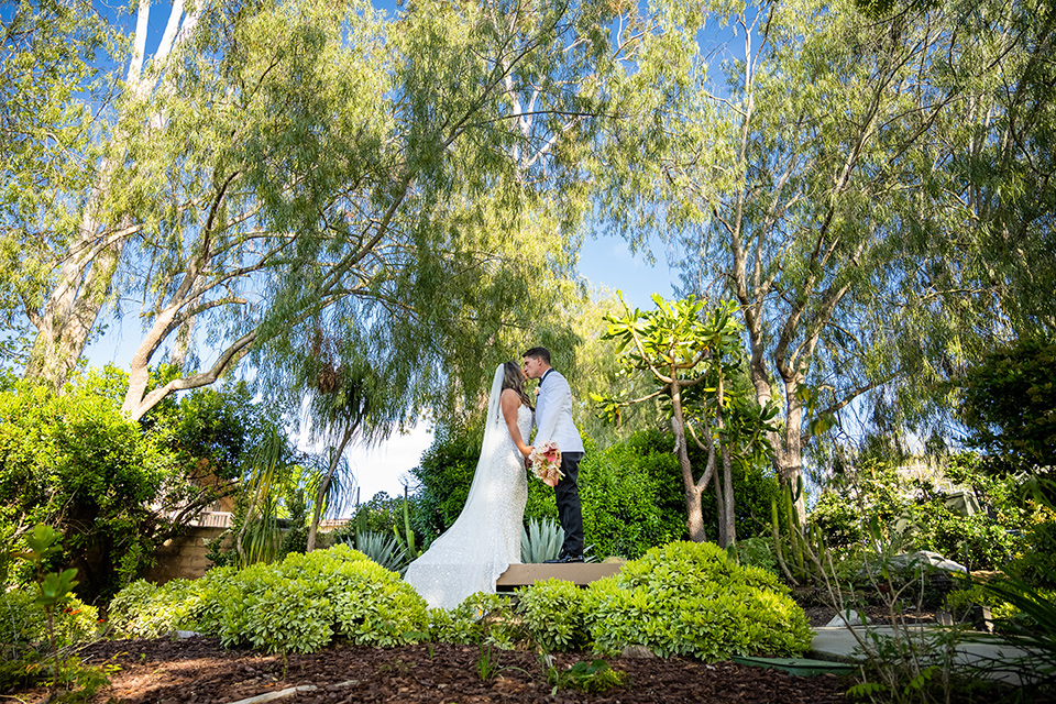  a modern black and white wedding with crystal details -the bride in a lace formfitting gown and the groom in a white + black tuxedo –couple kissing