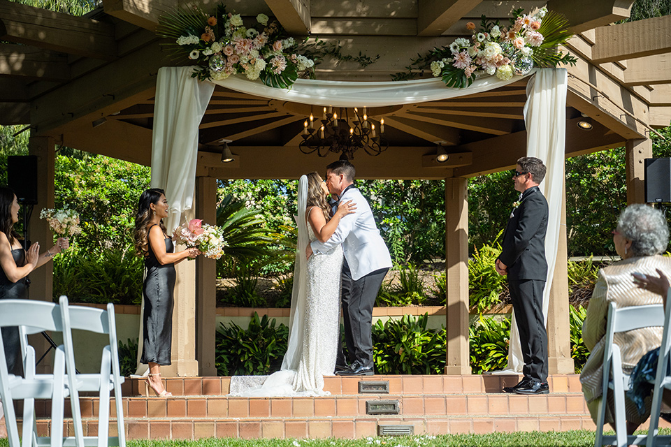  a modern black and white wedding with crystal details -the bride in a lace formfitting gown and the groom in a white + black tuxedo –first kiss