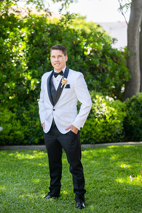  a modern black and white wedding with crystal details -the bride in a lace formfitting gown and the groom in a white + black tuxedo – groom in tuxedo