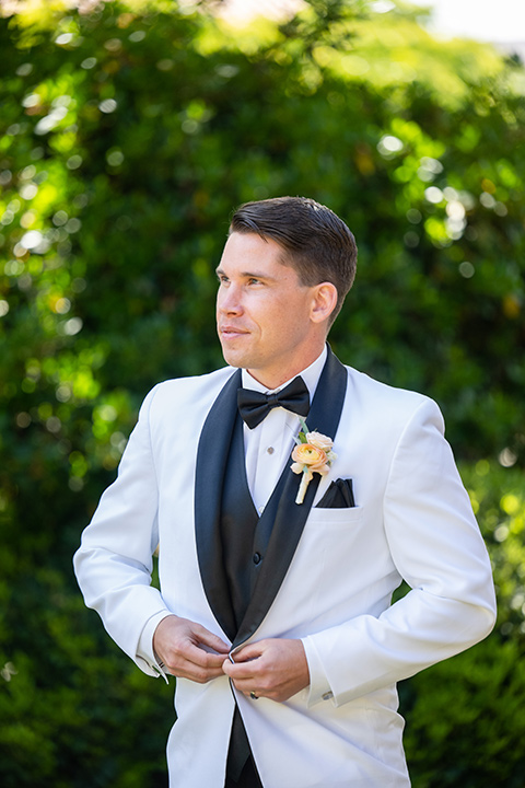  a modern black and white wedding with crystal details -the bride in a lace formfitting gown and the groom in a white + black tuxedo – groom in tuxedo 