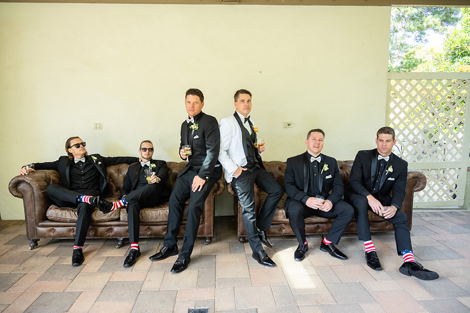  a modern black and white wedding with crystal details -the bride in a lace formfitting gown and the groom in a white + black tuxedo – groomsmen