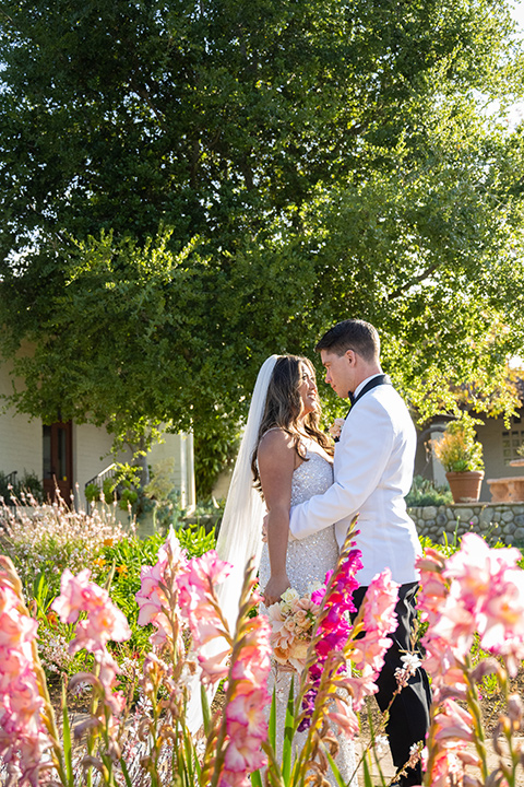  a modern black and white wedding with crystal details -the bride in a lace formfitting gown and the groom in a white + black tuxedo – bride and groom in meadow 