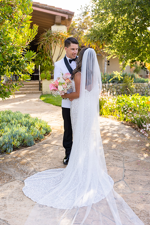  a modern black and white wedding with crystal details -the bride in a lace formfitting gown and the groom in a white + black tuxedo – bride and groom kissing