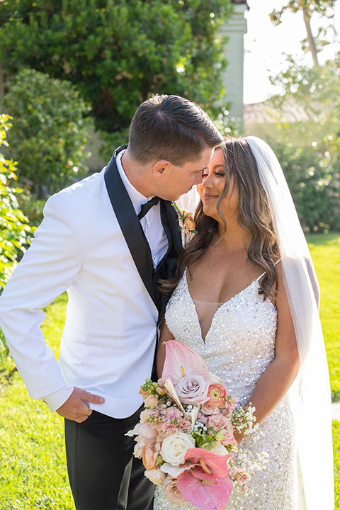  a modern black and white wedding with crystal details -the bride in a lace formfitting gown and the groom in a white + black tuxedo – couple kissing