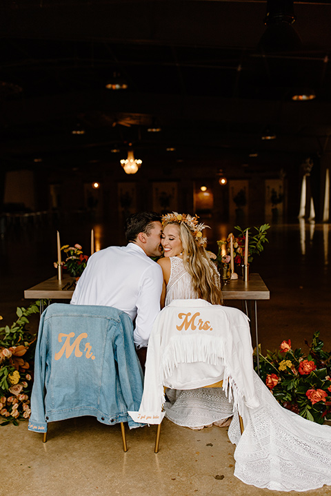  retro boho wedding with amber and brown color scheme – couple sitting at sweetheart table with jackets 
