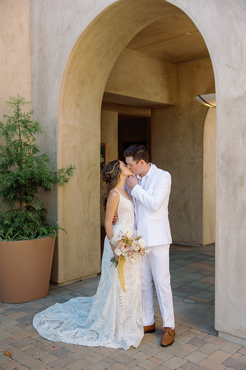  a colorful wedding inspired by the Amalfi Coast with the groom in different wedding day looks – couple embracing, groom in white suit 