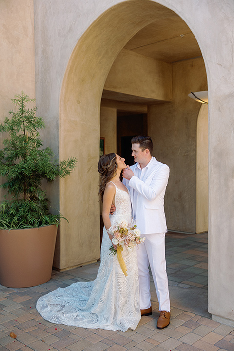  a colorful wedding inspired by the Amalfi Coast with the groom in different wedding day looks - couple embracing, groom in white suit 