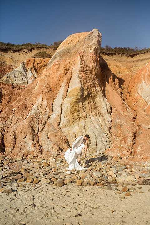  a neutral beachy elopement with the groom in a tan suit and the bride in a white lace dress – couple by the cliffs 