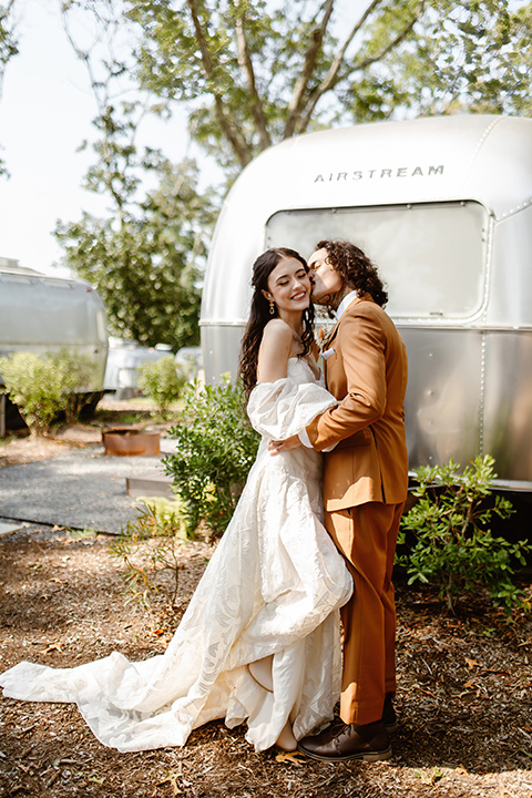  a boho caramel wedding inspo with an airstream and pampas grass – kissing in front of airstream 
