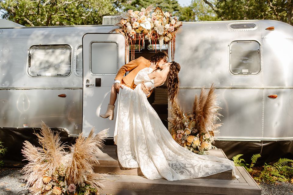  a boho caramel wedding inspo with an airstream and pampas grass – couple kissing in front of the airstream 