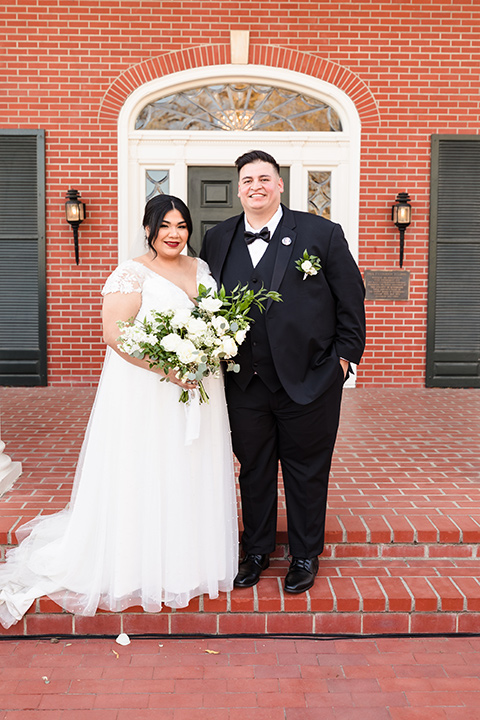  a romantic garden-rustic wedding with black and neutral décor elements and brick venue – couple looking at the camera 