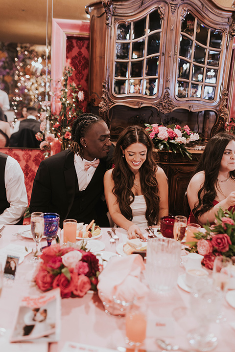  a grand pink and rose las vegas style wedding with bold trendy details – couple at table at the reception 