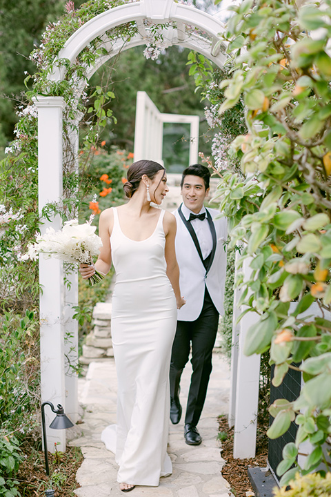  a monochromatic modern wedding at La Venta Inn with the bride in a sleek gown and the groom in a white tuxedo - couple walking around the venue 