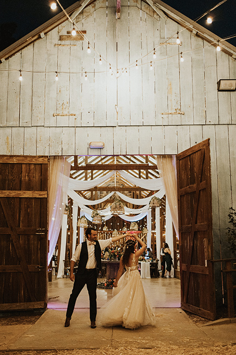  green and orange wedding in the woods with a rustic bohemian vibe – couple in reception barn 