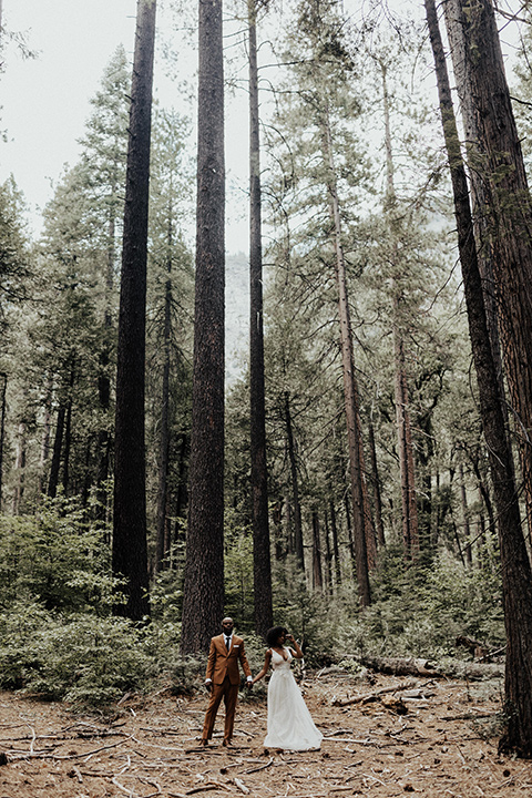  a woodland shoot in the sequoias with the groom in a caramel suit and the bride in a boho gown – couple standing in the trees 