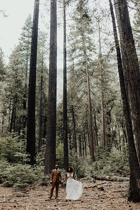  a woodland shoot in the sequoias with the groom in a caramel suit and the bride in a boho gown – couple standing in the trees 