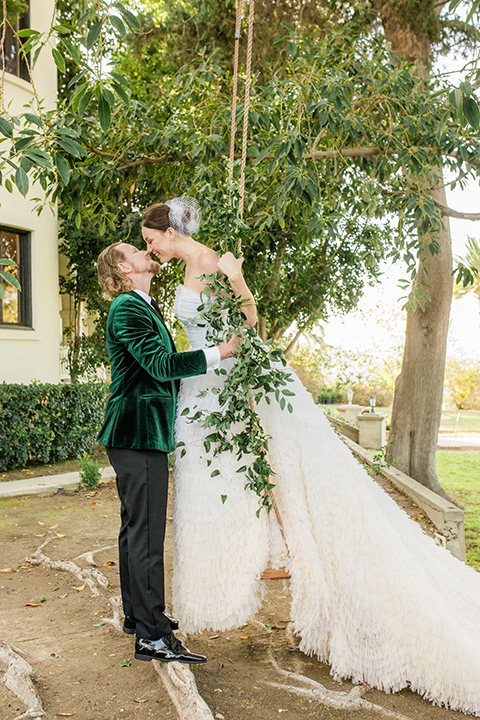  a dreamy whimsical wedding at a castle venue with the groom in a green velvet coat and the bride in a ballgown – couple on swing