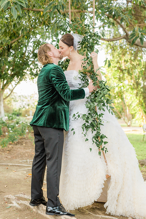  a dreamy whimsical wedding at a castle venue with the groom in a green velvet coat and the bride in a ballgown – couple on swing 